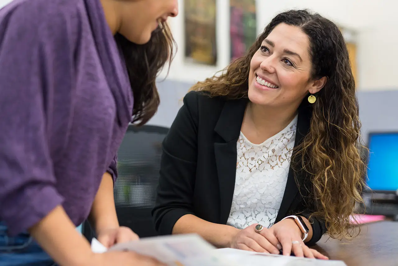 Two people smile while looking over letters and transcripts.