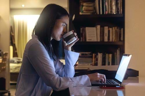 person drinking coffee at their laptop