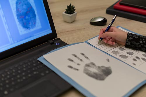 copy of ink handprint and looking at copies of fingerprints on computer