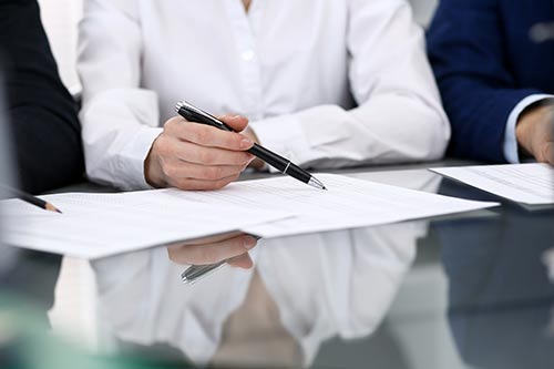 a person holding a pen pointing at a paper