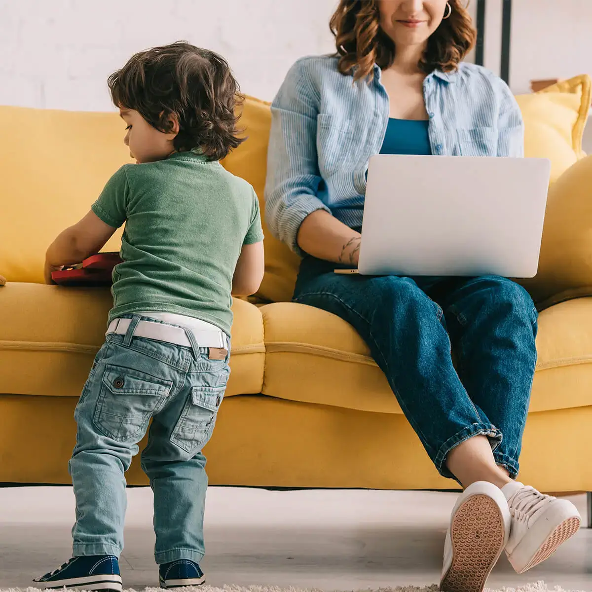 mom on computer and son standing by couch